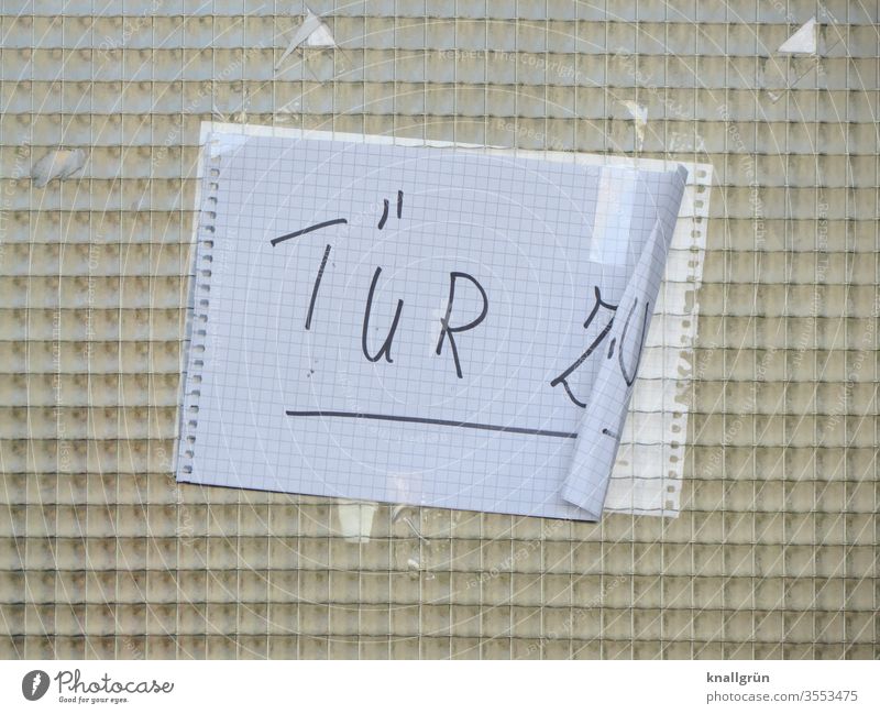 Drahtglasscheibe einer Hautür mit angeklebtem karierten DIN A4 Blatt, an einer Seite leicht eingerollt, mit der Aufschrift TÜR ZU Schilder & Markierungen