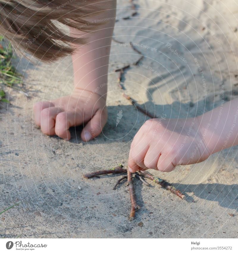 Kreativität ausleben - Detailaufnahme, kleiner Junge  legt im Sand einen Pfeil aus Stöckchen Kind Kindheit Kleinkind Mensch Arm Hand Haare Spielplatz Sommer