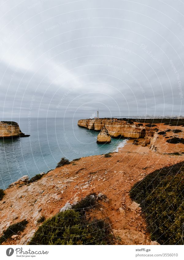 Ausblick über eine Bucht an der Algarve mit Felsküste und Leuchtturm Ferragudo Felsen Felswand Küste Meer Außenaufnahme Farbfoto Menschenleer Wellen