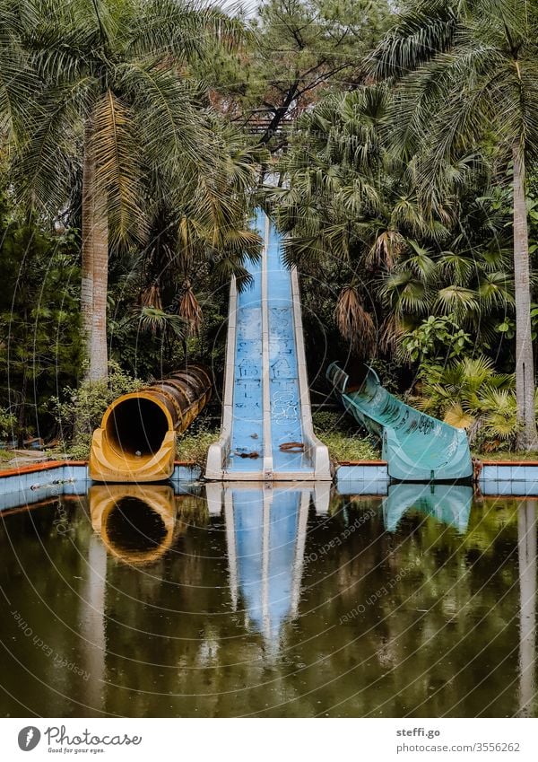 verlassene und verwilderte Wasserrutschen in einem Wasserpark im Dschungel mit Palmen in Vietnam lost places Hue Asien alt Menschenleer Farbfoto Verfall Tag