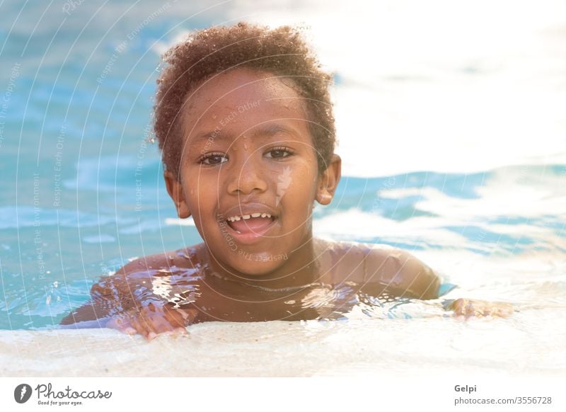 Kleines afrikanisches Kind spritzt im Schwimmbad Wasser Junge Sommer schwarz Afrikanisch Pool jung Kindheit Person Menschen klein Jugend spielen Sohn schön blau