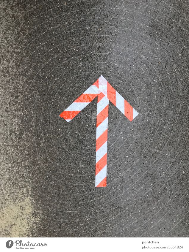 Orientierung. Ein Pfeil aus rot-weißem Kleband weist den Weg auf nasser Asphalt wegweiser klebeband richtung Schilder & Markierungen Zeichen Navigation