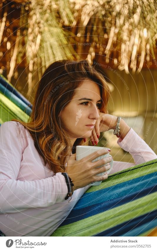Entspannte Frau mit Tasse Kaffee in Hängematte sich[Akk] entspannen Heißgetränk Windstille Lügen Barfuß Hof genießen Sommer Feiertag Urlaub Wochenende Becher