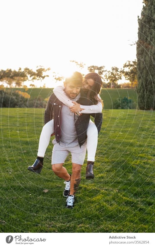 Glückliches Paar amüsiert sich auf der grünen Wiese Huckepack Zusammensein Liebe Feld Gras Spaß haben Partnerschaft Park positiv heiter jung Natur Bonden
