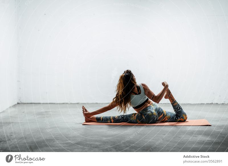Schlanke Frau praktiziert Yoga auf Matte üben Frontspalte Split hanumanasana Pose schlank Unterlage beweglich Asana sitzen Stock Sportbekleidung aktive Kleidung
