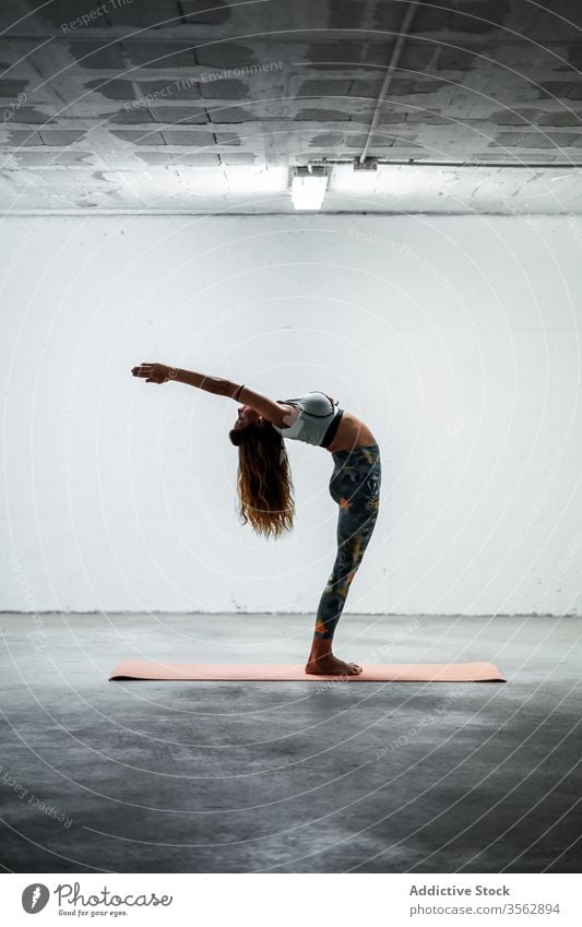 Schlanke Frau macht Yoga in Berg-Pose mit erhobenem Arm Gleichgewicht üben Windstille Stehende Rückbeuge schlanke Asana Unterlage beweglich stehen Stock