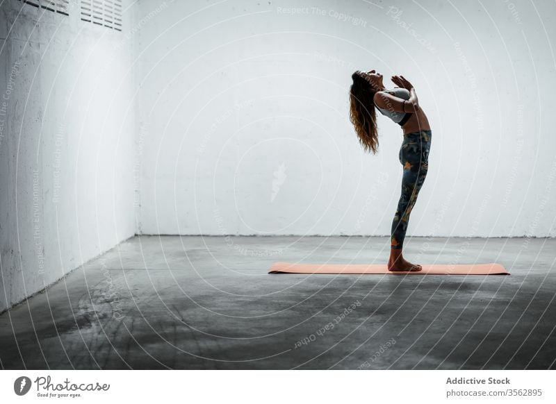 Schlanke Frau macht Yoga in Berg-Pose mit erhobenem Arm Gleichgewicht üben Windstille Stehende Rückbeuge schlanke Asana Unterlage beweglich stehen Stock