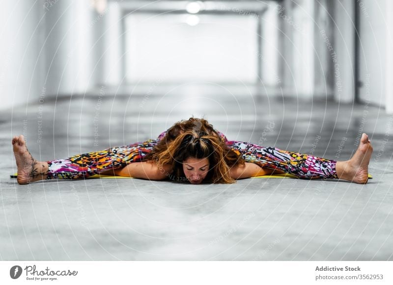 Junge Frau, die Yoga in sitzender Vorbeugeposition praktiziert üben Asana weitergeben Wegbiegung Garage Pose upavistha konasana positionieren fortgeschritten