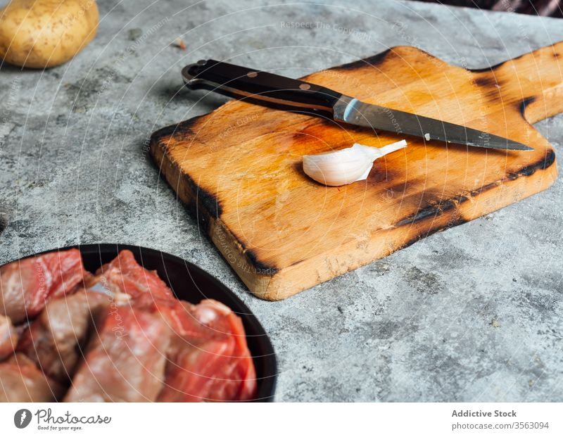 Knoblauchzehe auf dem Schneidebrett in der Küche Gewürznelke Messer frisch Fleisch Tisch roh Schalen & Schüsseln Rindfleisch Lebensmittel ungekocht vorbereiten
