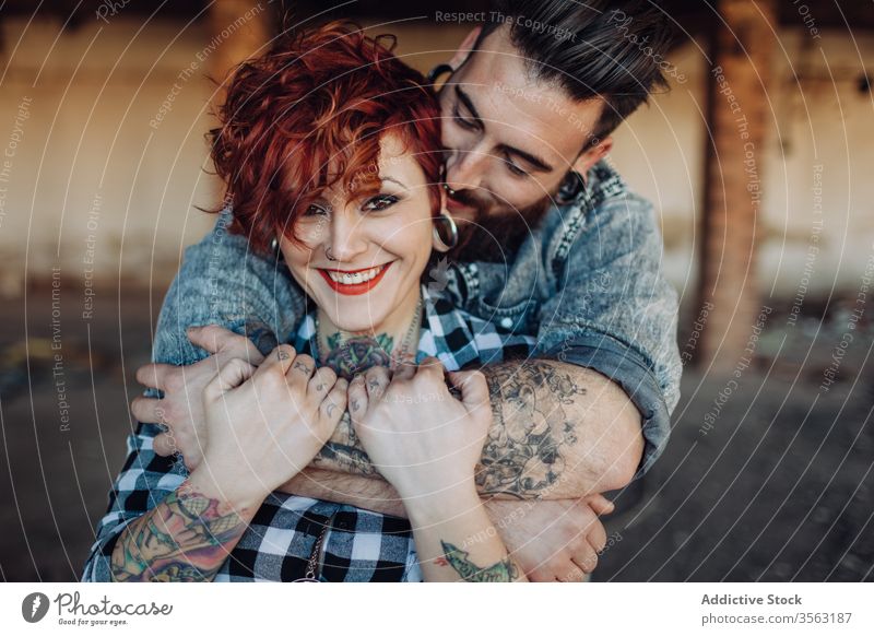 Glückliches junges Paar umarmt fast verwittertes Gebäude Liebe Umarmen Hipster Straße schäbig Zusammensein Umarmung Partnerschaft Tattoo Freund Freundin