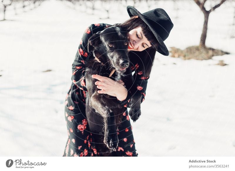 Stilvolle Frau mit Hund im Winterfeld Feld trendy Schnee schwarz Zusammensein Haustier Mode Park sich[Akk] entspannen Wald Baum Windstille Hut züchten kalt