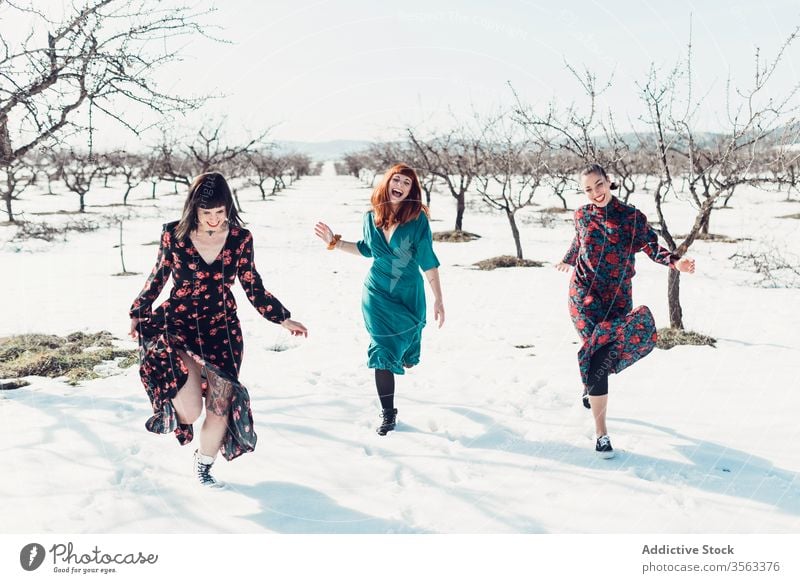 Fröhliche modische Frauen laufen auf Schnee Zusammensein Glück Spaß Winter Feld Freund heiter trendy Natur Mode Stil jung Freude Lächeln sich[Akk] entspannen