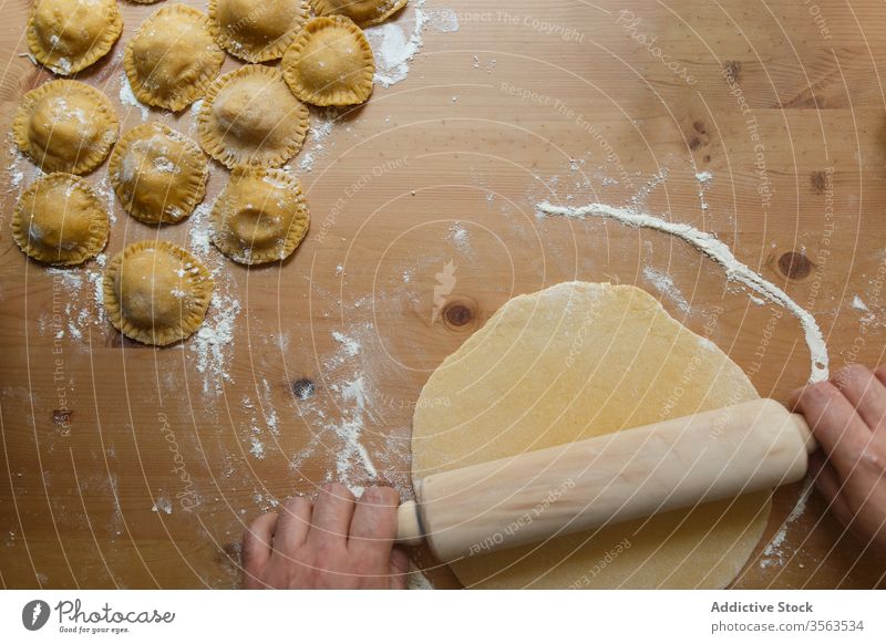 Männlicher Erntekoch rollt Teig mit Ravioli auf den Tisch Koch Nudelholz Teigwaren vorbereiten rollen kreisen roh Person rund hölzern Prozess Küche Lebensmittel