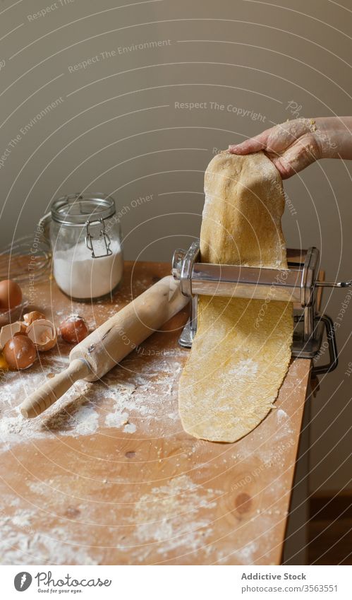 Anonyme Köchin rollt Teig aus, während sie die Nudelmaschine benutzt Frau Koch Spätzle rollen Maschine Teigwaren Gebäck elastisch Mehl Vorrichtung Küchengeräte