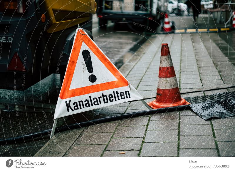 Ein Warnschild Warndreieck das auf Kanalarbeiten hinweist auf der Straße Warndreieeck Hinweisschild Schilder & Markierungen Schriftzeichen nass Regen Achtung