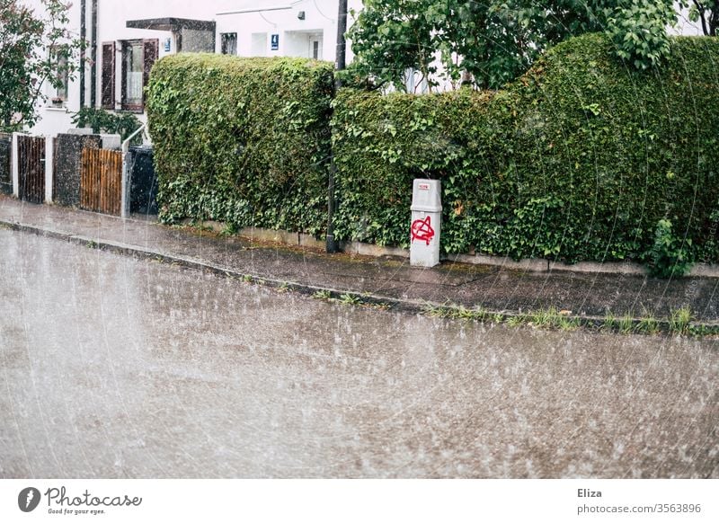 Eine Straße in einer Wohngegend bei starkem Regen Regenschauer leer nass schlechtes Wetter Herbst Bürgersteig Starkregen trist grau grün Sommerregen