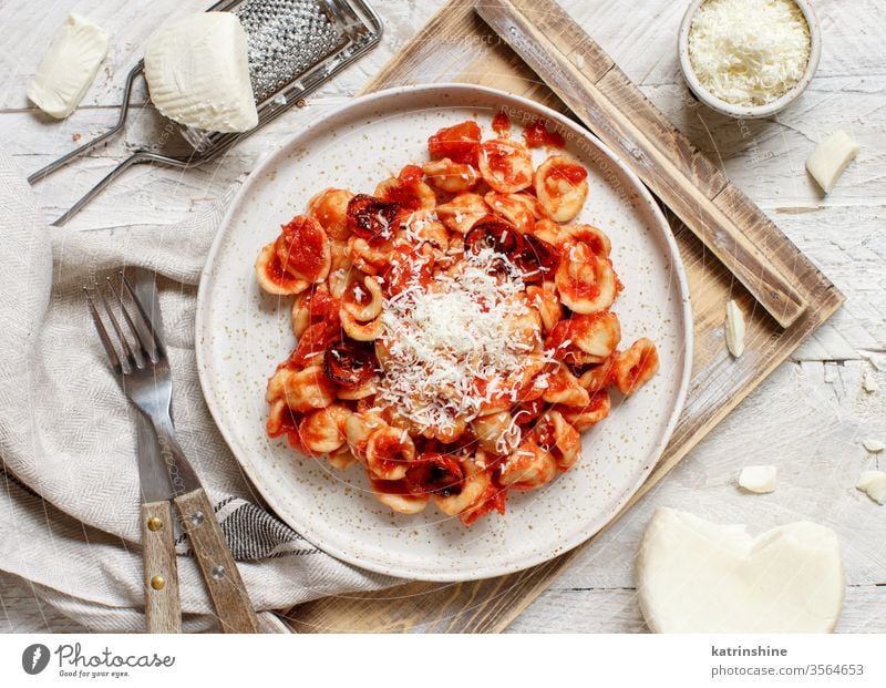 Süditalienische Pasta-Orecchiette mit Tomatensauce und Cacioricotta-Käse Spätzle Italienisch Apulien Saucen sugo Draufsicht Tablett weiß Reibeisen hölzern
