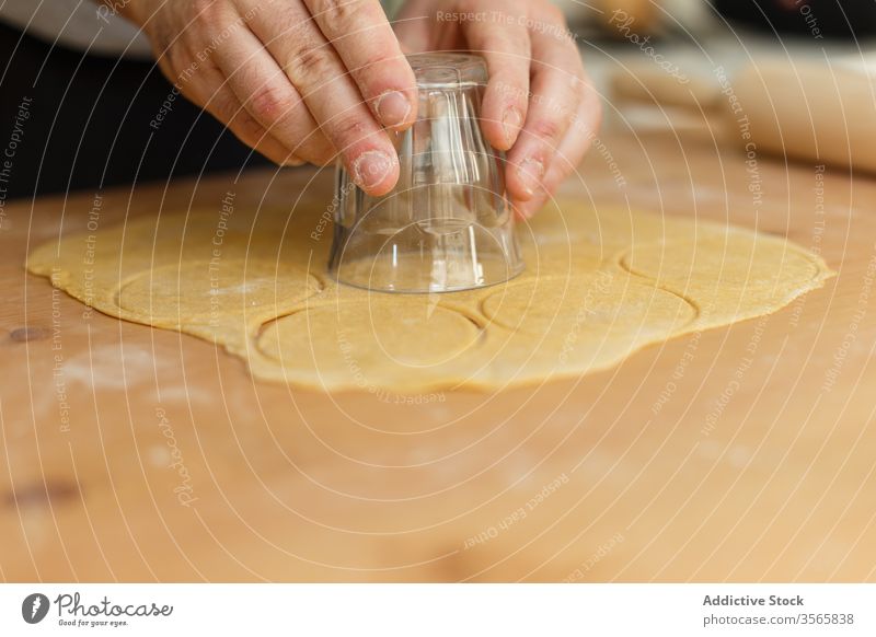 Anonymer männlicher Koch benutzt Glas zum Schneiden runder Formen für Ravioli Kutter Teigwaren Bestandteil Presse Nudelholz kreisen Tisch hölzern vorbereiten