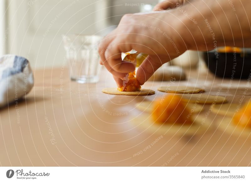 Erntehelfer, der Ravioli mit Kürbisfüllung füllt Teigwaren Zeug vorbereiten kreisen Koch Tisch rund hölzern Prozess Küche Lebensmittel kulinarisch selbstgemacht