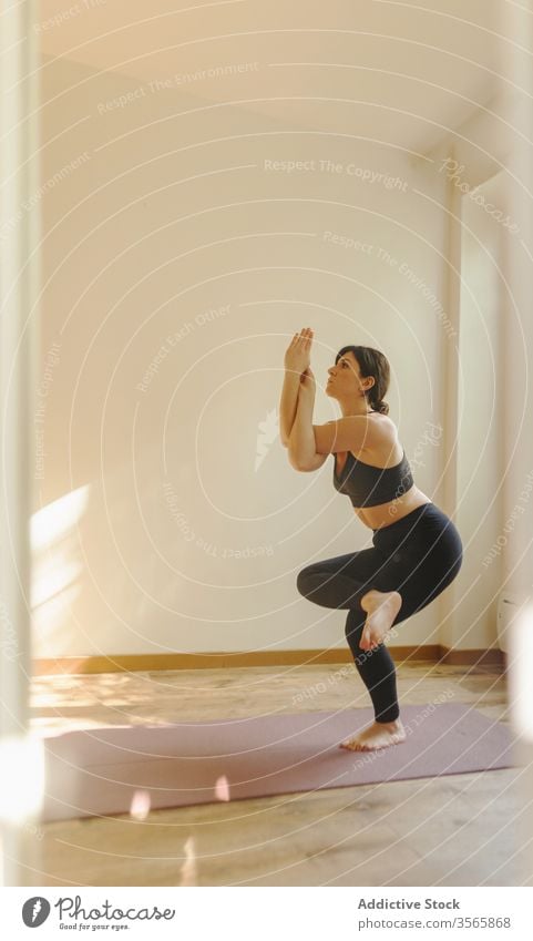 Sportlerin, die zu Hause in Adlerpose auf der Matte steht Frau Adler-Pose Yoga Gleichgewicht meditieren Gesunder Lebensstil Vitalität üben Wellness Unterlage
