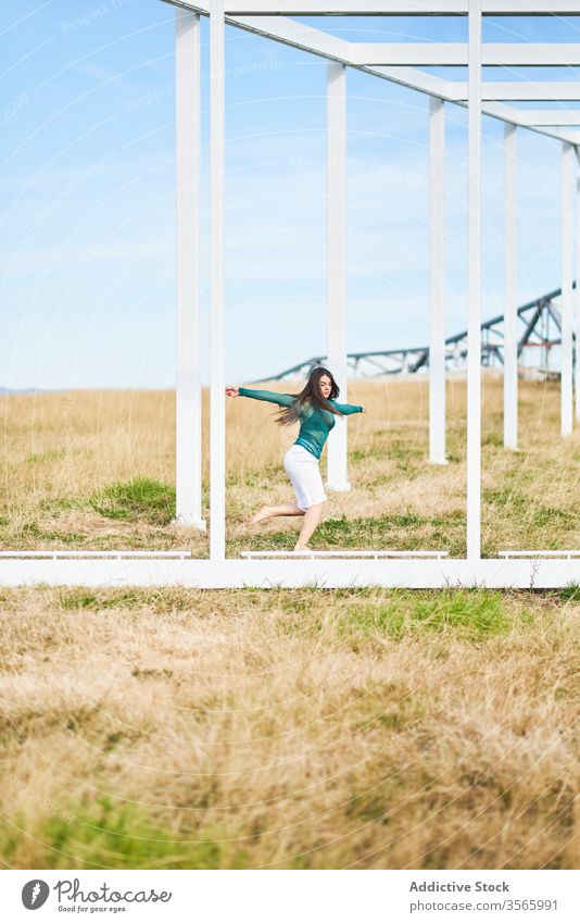Junge Frau tanzt in der Nähe einer Metallkonstruktion auf dem Land Feld Landschaft Tanzen fallen Konstruktion Wegbiegung Geometrie Fliege modern Straße Kunst