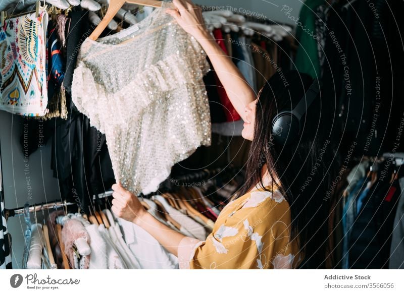 Junge attraktive Frau mit Kleidung in der Garderobe Kleiderschrank Kleidungsstück pflücken heimwärts Robe Bekleidung Stoff wählen Outfit Mode Stil brünett Wahl