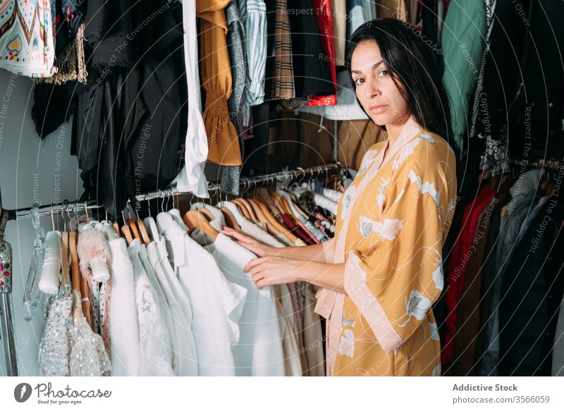 Junge attraktive Frau mit Kleidung in der Garderobe Kleiderschrank Kleidungsstück pflücken heimwärts Robe Bekleidung Stoff wählen Outfit Mode Stil brünett Wahl