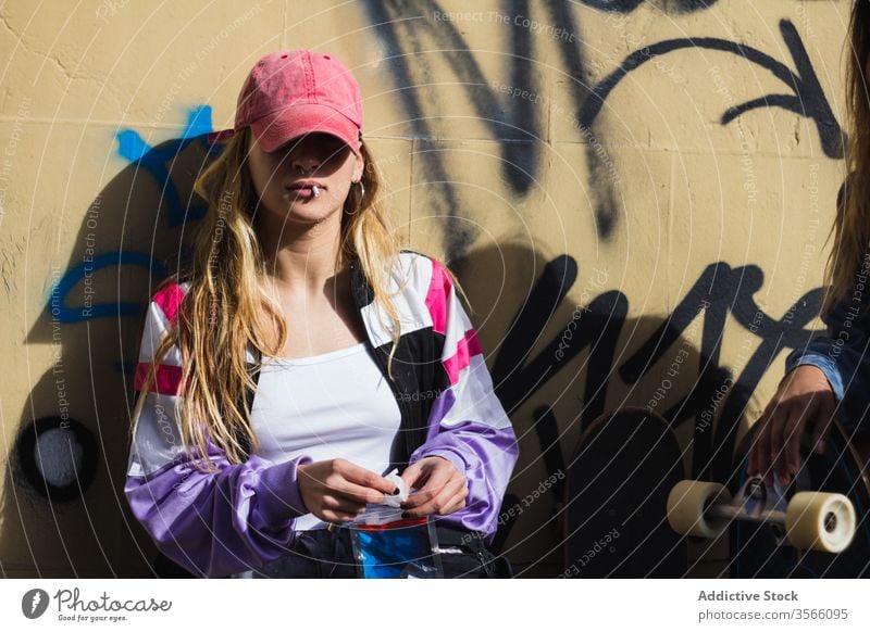 Selbstbewusste weibliche Hipster rauchen auf der Straße Rauch Frau Skateboard Graffiti tausendjährig selbstbewusst auflehnen Freundin Skater Streetstyle