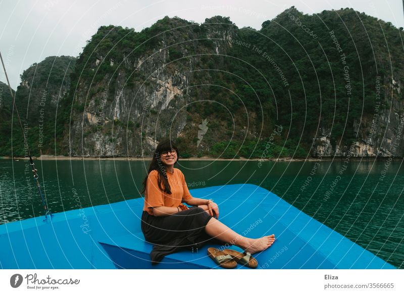Junge Frau sitzt am Bug eines Bootes und lacht in die Kamera. Halong Bay in Vietnam. lachen Urlaub Reisen Schiff Ausflug Sehenswürdigkeit Aussicht Meer Wasser