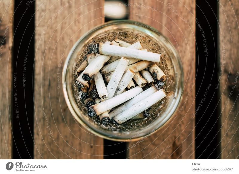 Ein runtes Glas als Aschenbecher mit vielen Zigarettenstummeln darin aus  Vogelperspektive - ein lizenzfreies Stock Foto von Photocase