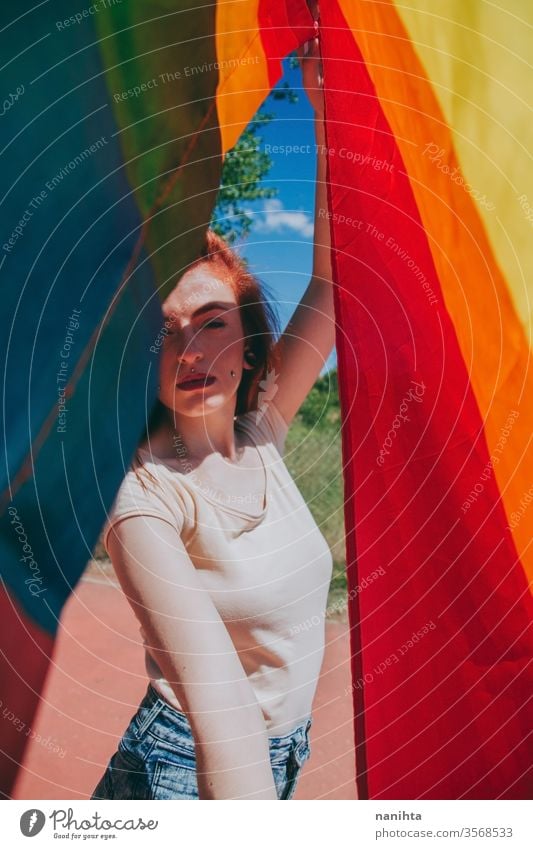 Junge Frau bedeckt von einer Regenbogenfahne lgbti schwul Stolz Party Fahne Homosexualität lesbisch Farbe farbenfroh im Freien sozial Problem Geschlecht