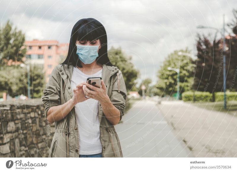 Frau mit medizinischer Maske mit seinem Smartphone auf der Straße Coronavirus Junge Frau Virus Seuche Pandemie Quarantäne covid-19 Telefon App Mobile