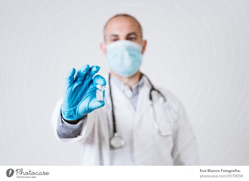 Arzt Mann mit Fläschchen. mit Schutzmaske und Handschuhen während der Pandemie Coronavirus covid 2019. Gesundheitsversorgung und medizinisches Konzept Spritze
