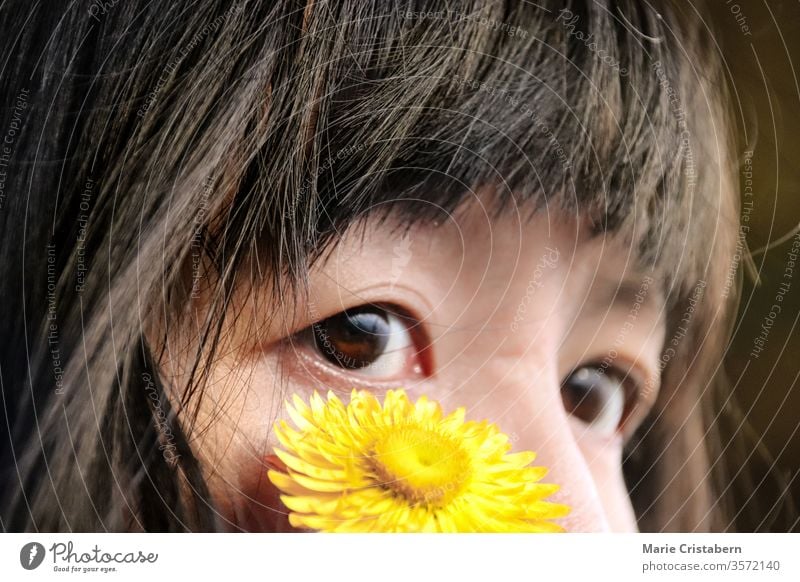 Nahaufnahme einer gelben Blume auf dem Gesicht eines asiatischen Mädchens mit Mandelaugen Unschuld Reinheit Kindheit Porträt Glück Farbfoto Ausdruck Gefühle