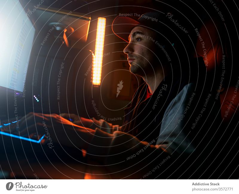 Junger Mann mit Headset spielt zu Hause in dunkler Kammer Videospiel Spieler Verschlussdeckel spielen dunkel Monitor Computer allein heimwärts Gerät pc Drahtlos