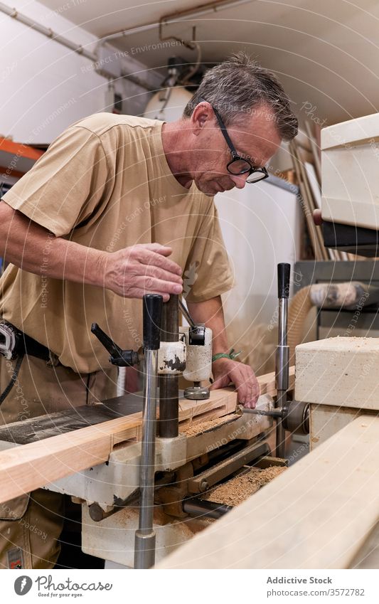 Fleißiger Zimmermann bohrt Holz in modernem Arbeitsraum Zimmerer bohren Schreinerei Nutzholz Holzarbeiten Verarbeitung Kunsthandwerk Mann Werkstatt Arbeitsplatz