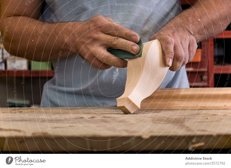 Handwerkliches Polieren von Holzdetails mit Sandpapier in der Schreinerei Kunstgewerbler polnisch Schleifpapier Detailaufnahme Kontrolle Holzarbeiten Meister