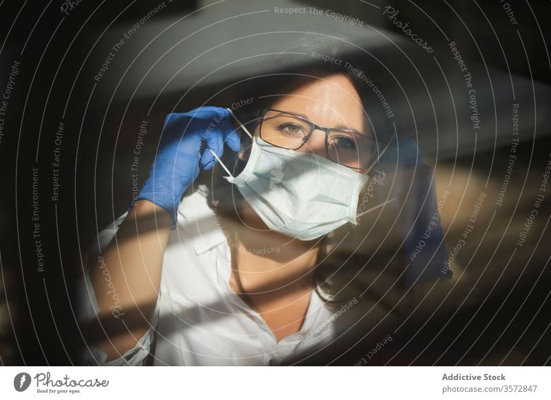 Frau mit Schutzmaske und Handschuhen bei der Arbeit zu Hause Coronavirus Mundschutz behüten COVID Sicherheit Pandemie Risiko Fenster Krankheit ernst Ausbruch
