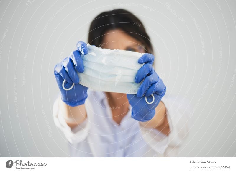 Anonyme Frau mit Schutzmaske und Handschuhen zu Hause Coronavirus Mundschutz behüten zeigen COVID Sicherheit Pandemie Risiko Krankheit ernst Ausbruch