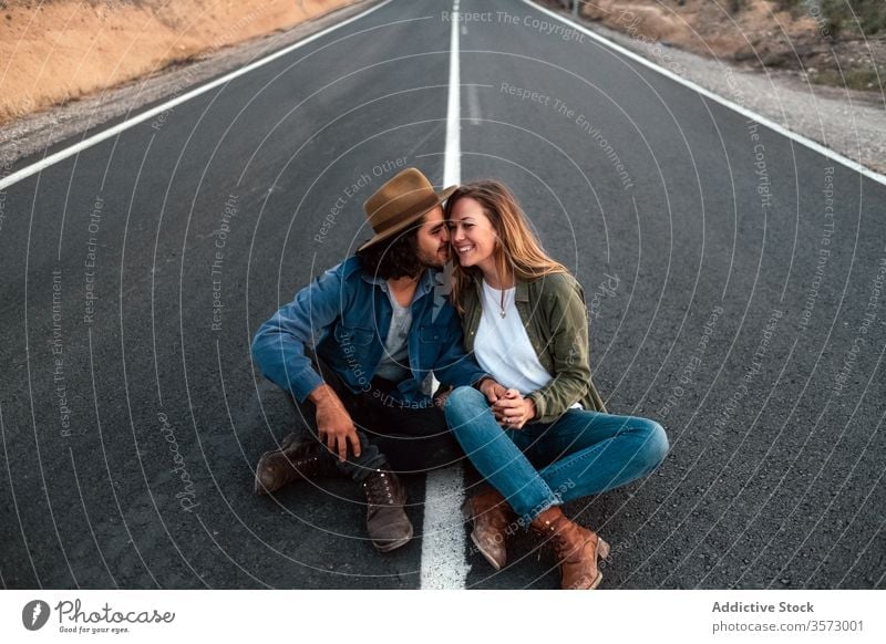 Glückliches Paar sitzt auf der Strasse und berührt sich an den Nasen Lächeln Berührungsnase Straße Termin & Datum Liebe Landschaft reisen Angebot Zusammensein