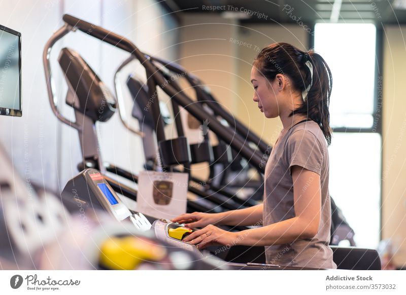 Junge ethnische Sportlerin läuft auf dem Laufband, während sie in einem modernen Fitnessstudio trainiert Frau laufen Herz Übung Athlet Training Gesundheit