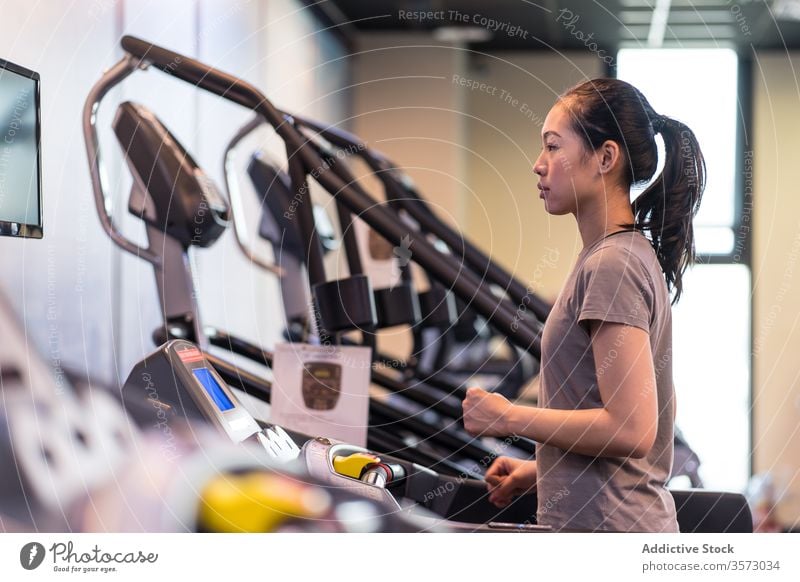 Junge ethnische Sportlerin läuft auf dem Laufband, während sie in einem modernen Fitnessstudio trainiert Frau laufen Herz Übung Athlet Training Gesundheit