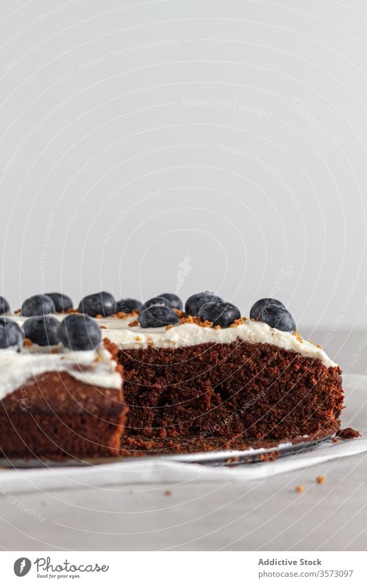 Ein Stück frischer Schokoladenkuchen mit Blaubeeren und Sahne dekoriert auf dem Küchentisch Spielfigur Kuchen gepeitscht Scheibe Schwamm Biskuit weiß