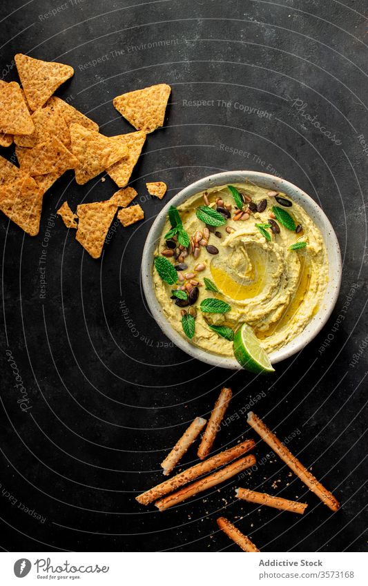 Hummus-Erbsen auf einer Schale in der Nähe von Crackern Antipasti Kichererbsen Erdöl Püree Gesundheit Minze Libanese arabisch eintauchend organisch