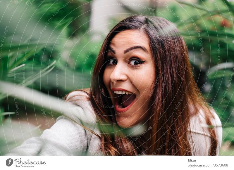 Junge Frau lacht draußen in der Natur freudig euphorisch positiv überrascht in die Kamera Porträt Grimasse jung hübsch erstaunt Quatsch Mädchen Gesicht schön
