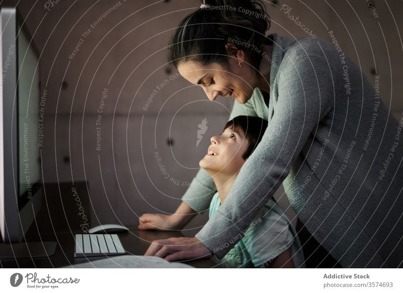 Mutter hilft Kind bei den Hausaufgaben während des Online-Studiums online lernen Bildung Computer Hilfsbereitschaft erklären Zusammensein Mama heimwärts