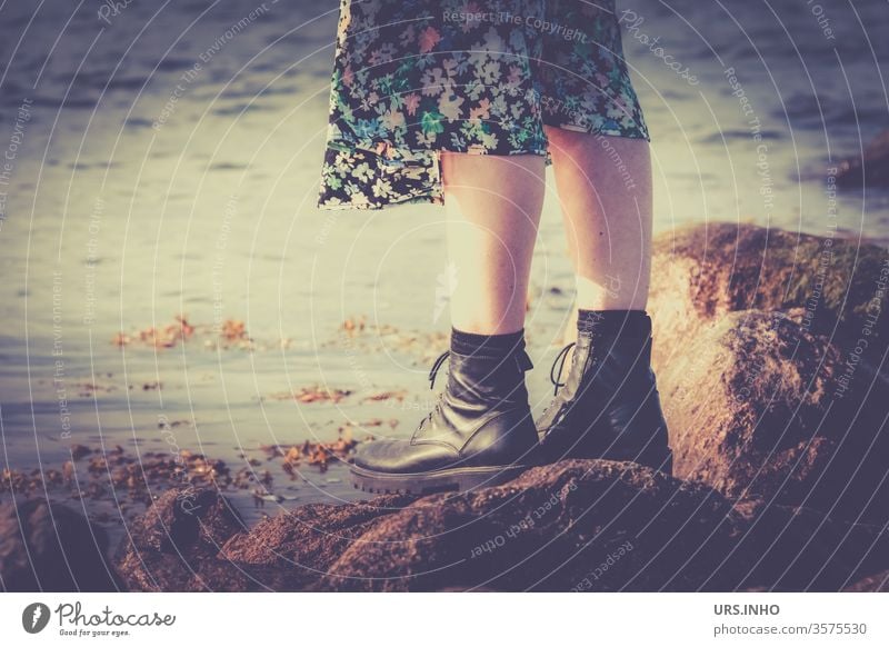 Füße einer Frau mit Boots und Blümchenrock stehen auf großen Steinen am Meer Beine vintage Außenaufnahme Strand Naturstrand Ferien & Urlaub & Reisen Erholung