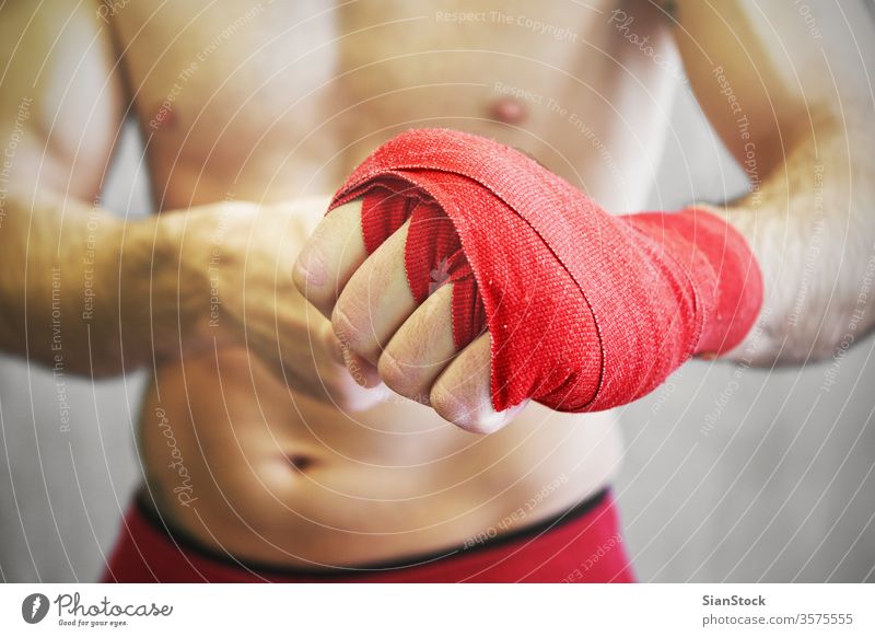 Der Mann umhüllt seine Hände mit roten Boxentüchern. Boxer Hand Wraps umhüllen Boxsport kämpfen Arme Hintergrund Handgelenk Athlet Kämpfer Fitness stark