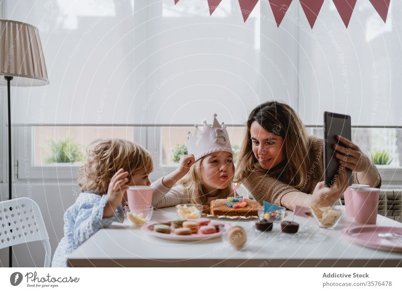 Fröhliches kleines Mädchen macht während der Geburtstagsfeier einen Videoanruf auf Tablet Mutter Tochter feiern Spaß Glück abgelegen heimwärts Entfernung