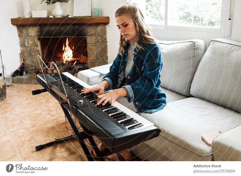 Junge Frau spielt zu Hause elektronisches Klavier spielen heimwärts Musik jung Instrument gemütlich Musiker elektrisch Sofa Komponist Feuerstelle Synthesizer